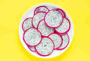 Free photo closeup of a plate of dragon fruit slices on yellow background