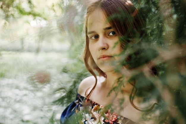 Free photo closeup portrait of a beautiful brunette in dress next to the leaves