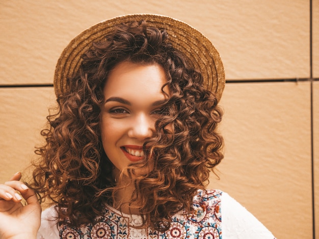 Closeup portrait of beautiful smiling model with afro curls hairstyle dressed in summer hipster white dress.