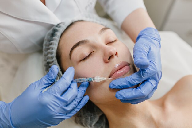 Closeup portrait of beautiful woman during cosmetology therapy in beauty salon. Botox, lips, injecting, professional  procedures, lifting, rejuvenation, modern devices, healthcare