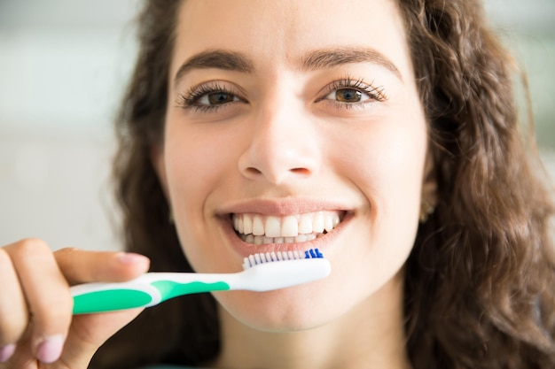 Free photo closeup portrait of beautiful young woman brushing teeth in dental clinic