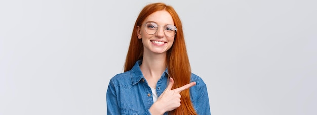 Free photo closeup portrait cute cheerful redhead foxy girl in glasses showing place to click website follow or