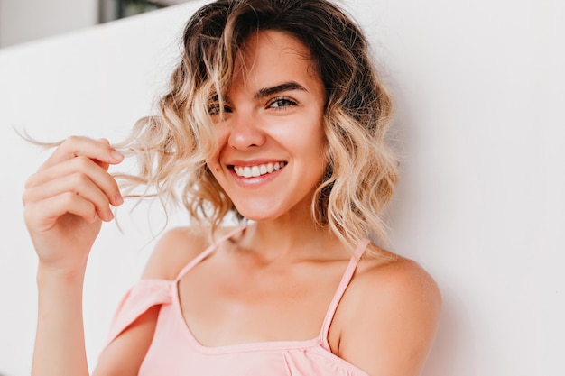 Closeup portrait of enchanting laughing girl playing with wavy hair Photo of interested tanned woman with pretty smile