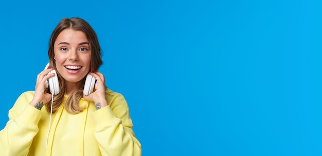 Free photo closeup portrait of excited happy smiling blond girl in yellow hoodie takeoff headphones and grinnin