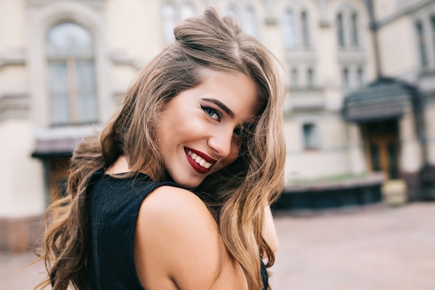 Closeup portrait of pretty girl with long curly hair smiling