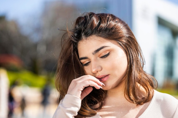 Closeup portrait of young beautiful girl puts her hand to her mouth and looking down High quality photo