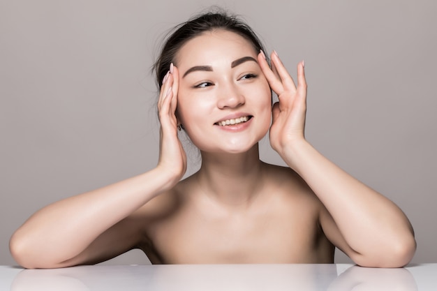 Closeup portrait of young woman face skin care with cosmetics isolated on gray wall