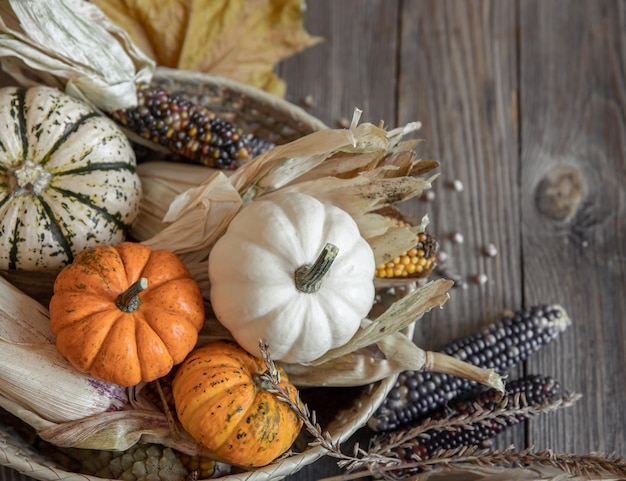 Closeup of pumpkin corn and autumn leaves on a wooden background