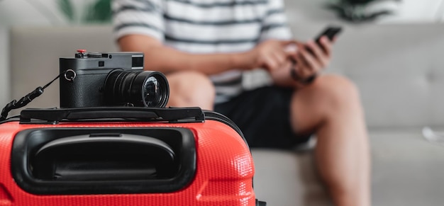 Free photo closeup of retro camera on luggage with traveler man sitting on sofa background young man has packed his luggage and is ready to go travel holiday and vacation concept