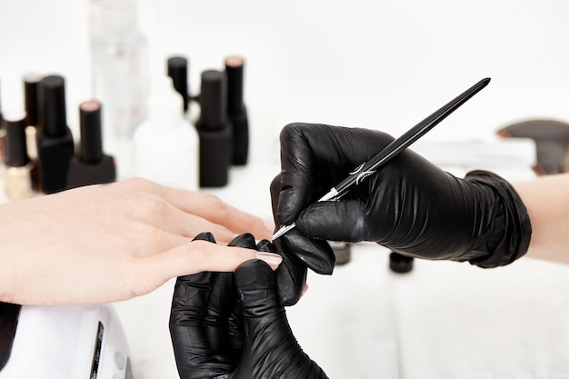 Closeup of rofessional nail artist hands holding woman hand, doing trendy geometric nail art.