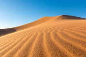 Free photo closeup of sand ripples on sand dunes in a desert against  clear blue sky