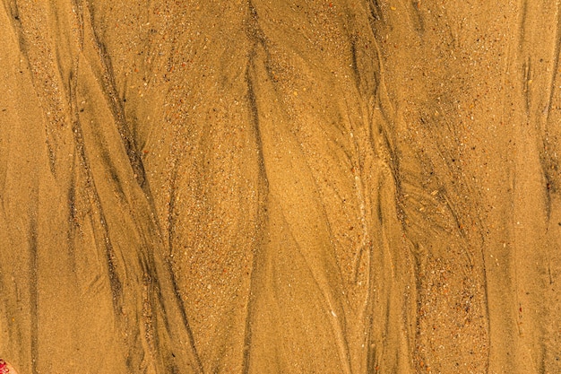 Closeup of sand with tidal ways and shells on the beach full frame texture background