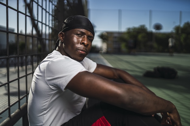 Closeup shot of an African-American male in a white shirt sitting on a concrete floor