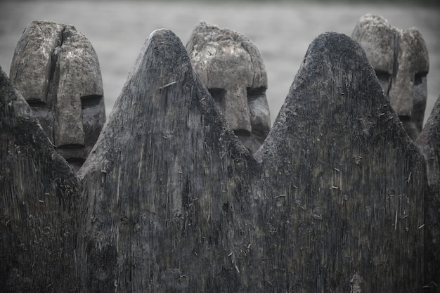 Free Photo closeup shot of ancient danish viking figures made with stone behind a wooden fence