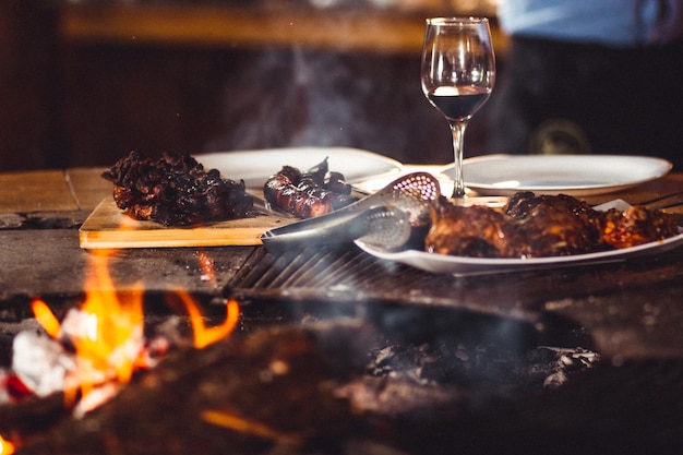 Free Photo closeup shot of barbequed meat and a glass of wine near the fireplace