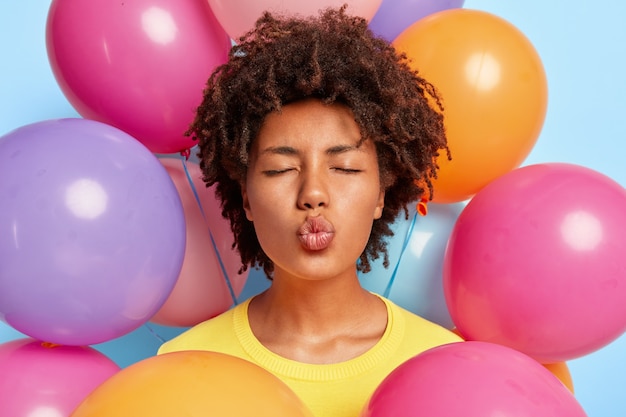 Closeup shot of beautiful young woman posing surrounded by birthday colorful balloons