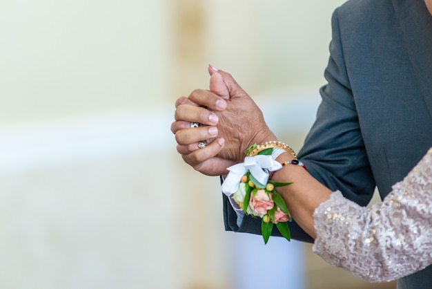 Closeup shot of a bride and a groom holding hands while dancing