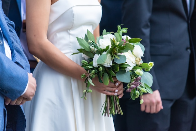 Closeup shot of a bride holding her beautiful bouquet standing at the altar