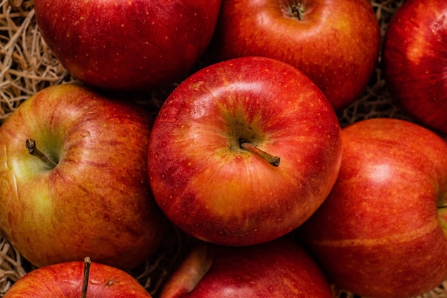 Closeup shot of a bunch of tasty looking red apples on a hay surface