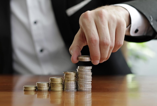 Closeup shot of a businessman's hands counting stacks of coins after business success