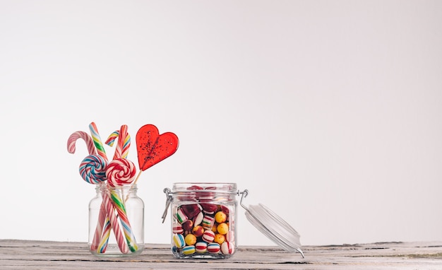 Closeup shot of candy canes and other candies in glass jars on a wooden surface