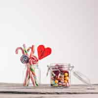 Free photo closeup shot of candy canes and other candies in glass jars on a wooden surface