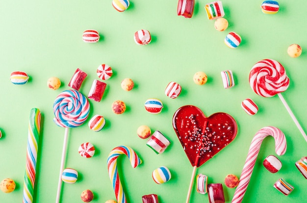 Closeup shot of candy canes and other candies on a green background