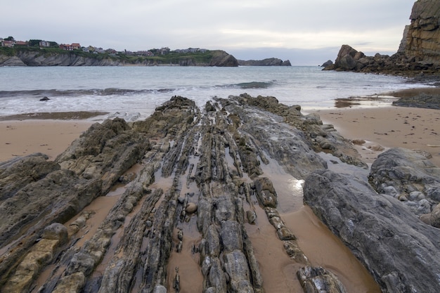 Free Photo closeup shot of a cliffy seashore near a wavy sea under a cloudy sky