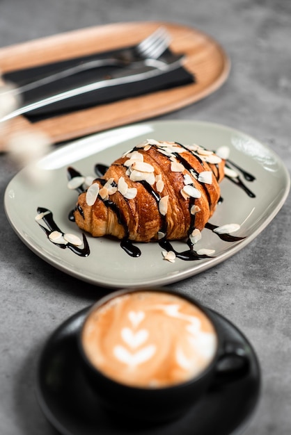 Free photo closeup shot of a croissant on a plate covered in chocolate in a cafe