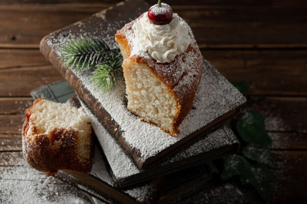 Closeup shot of delicious dessert with cream, powdered sugar, and a cherry on top on books