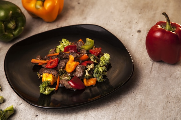 Free photo closeup shot of a delicious and healthy meal with beef and grilled vegetables in a black plate