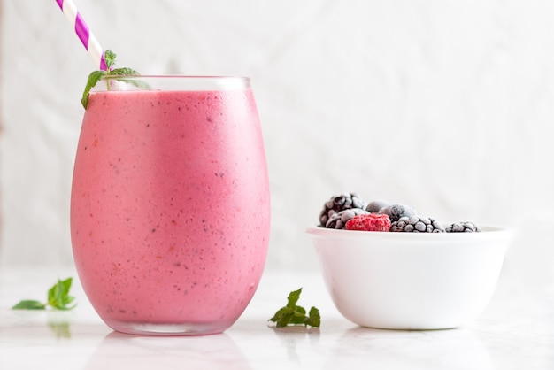 Free photo closeup shot of a delicious mix berry milkshake with different berries in a bowl next to it