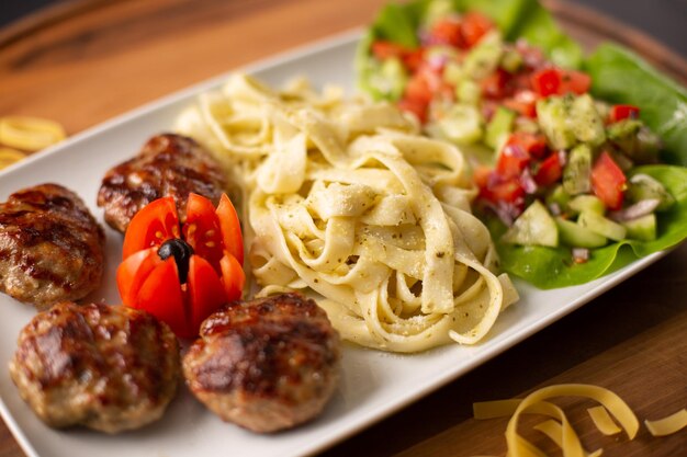 Closeup shot of delicious pasta served with meatballs and a healthy salad