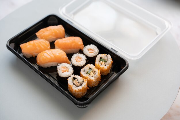 Closeup shot of delicious sushi rolls in a plastic box on a white surface