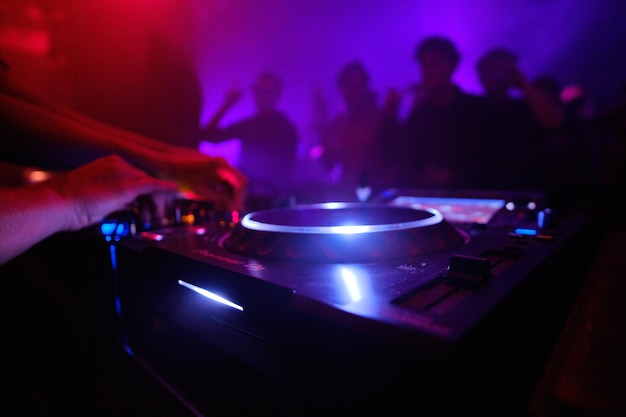 Free photo closeup shot of dj's equipment and the people dancing in the club