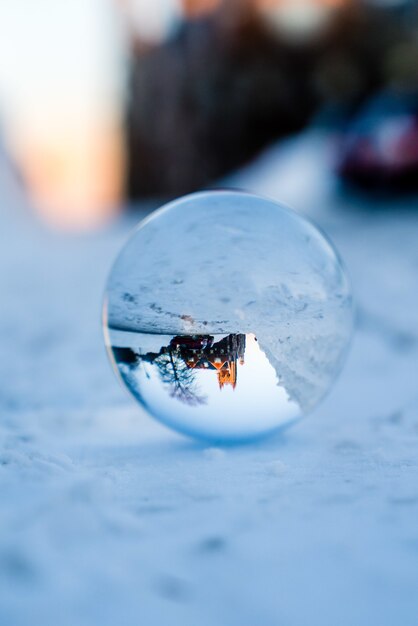 Closeup shot or a drop of water on the snowy ground reflecting a part of the city