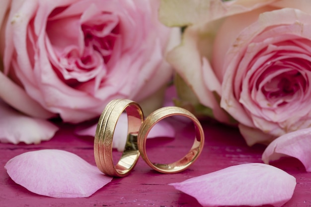 Closeup shot of engagement rings with beautiful pink roses on the table