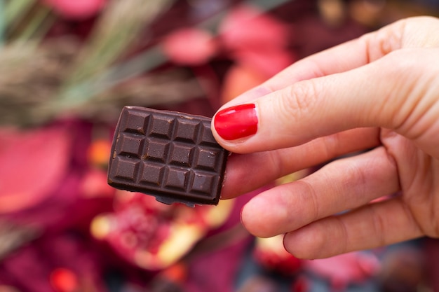 Free photo closeup shot of a female holding a piece of raw vegan chocolate with a blurred background