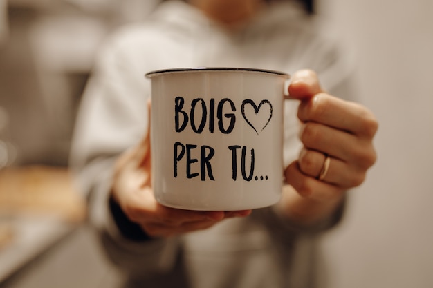 Closeup shot of a female holding a white ceramic mug with song lyrics printed on it