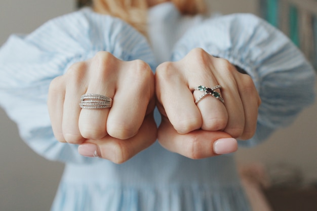 Closeup shot of a female wearing beautiful rings on both hands and showing with fists