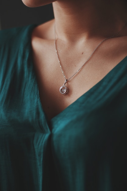 Free photo closeup shot of a female wearing a beautiful silver necklace with a diamond pendant