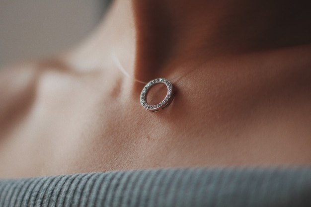 Free Photo closeup shot of a female wearing a beautiful silver necklace with a pendant