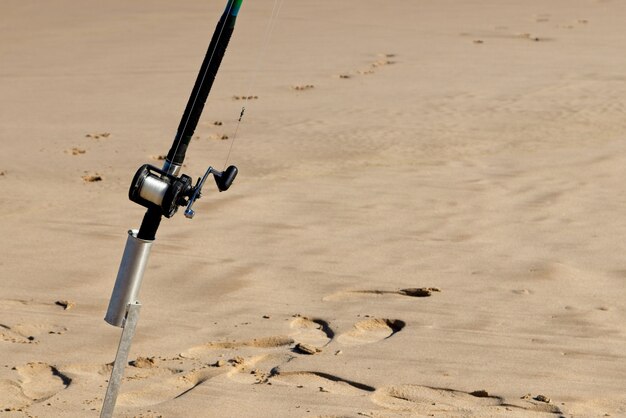 Closeup shot of a fishing pole in a sandy surface