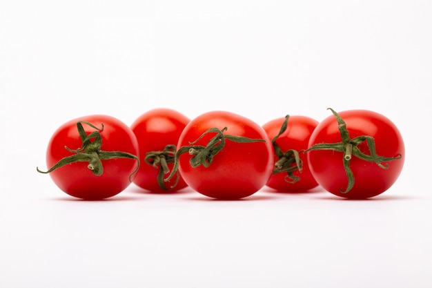 Free photo closeup shot of five cherry tomatoes on a white wall - perfect for a food blog