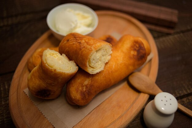 Closeup shot of fried egg rolls with a small bowl of dipping cream on a wooden board