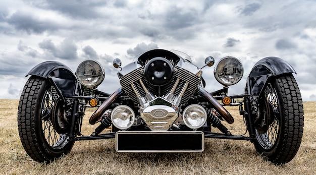 Free photo closeup shot of the front of a black vehicle parked on a dry field under a cloudy sky