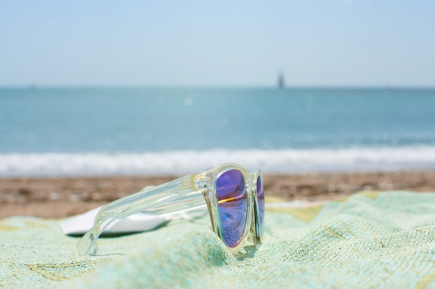 Free photo closeup shot of funky sunglasses on the beach towel on a sand beach