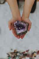 Free photo closeup shot of a girl holding a multicolored rock in her hands over a white surface