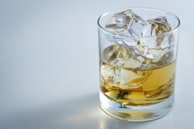 Closeup shot of a glass full of ice and some whiskey isolated on a white background