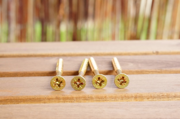 Closeup shot of golden cross screws on a golden table